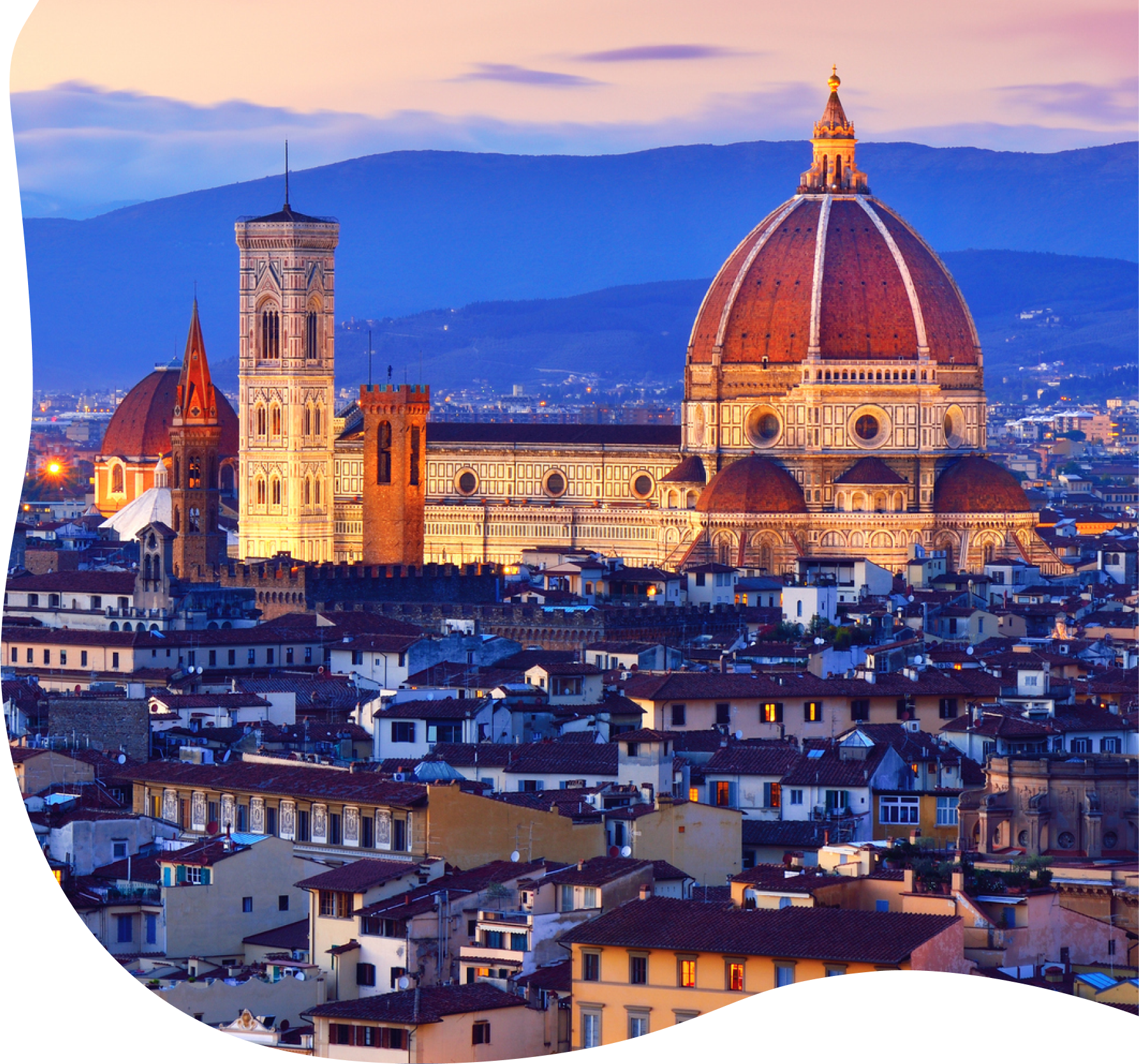 Large church in center of dense city with mountains in the backdrop