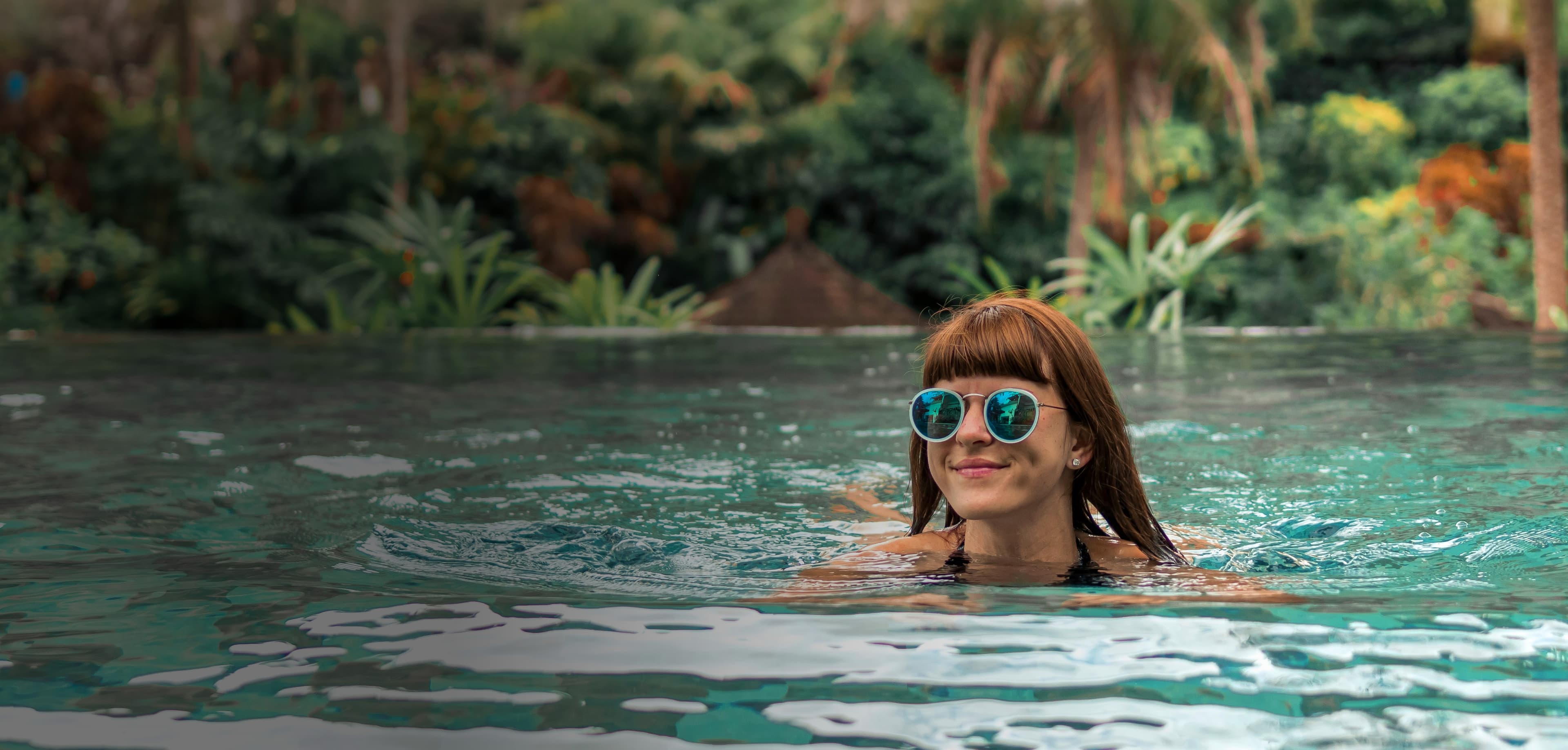 luxury traveler swimming in tropical landscape with sunglasses